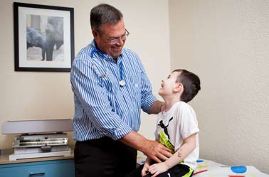 A photo of a doctor treating a male child patient.